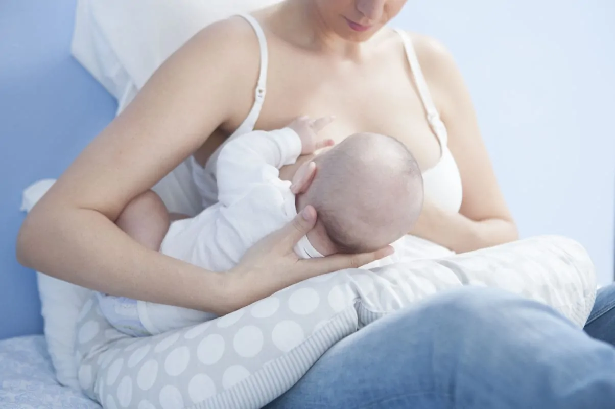 Frau stillt baby mit Stillkissen Kliniktasche geburt Utensilien für das Wochenbett
