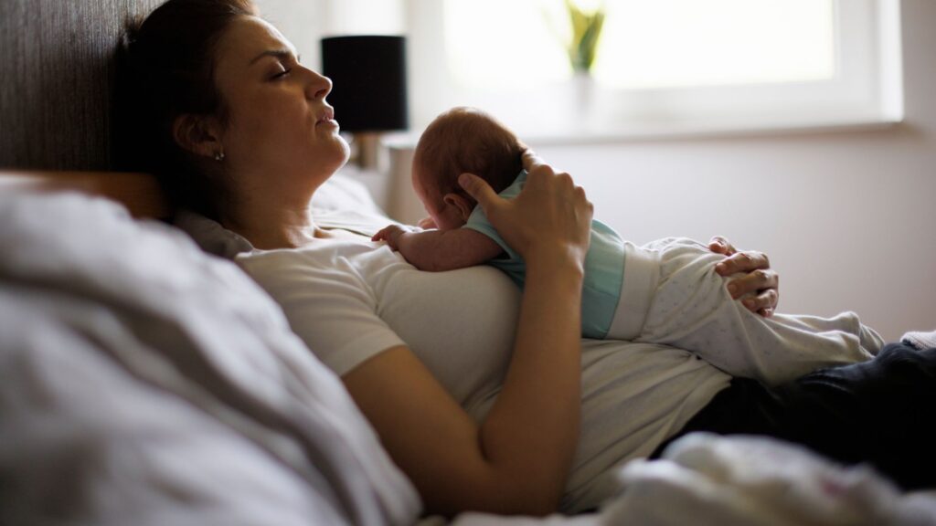 junge Mutter mit Neugeboenem Wochenbett
