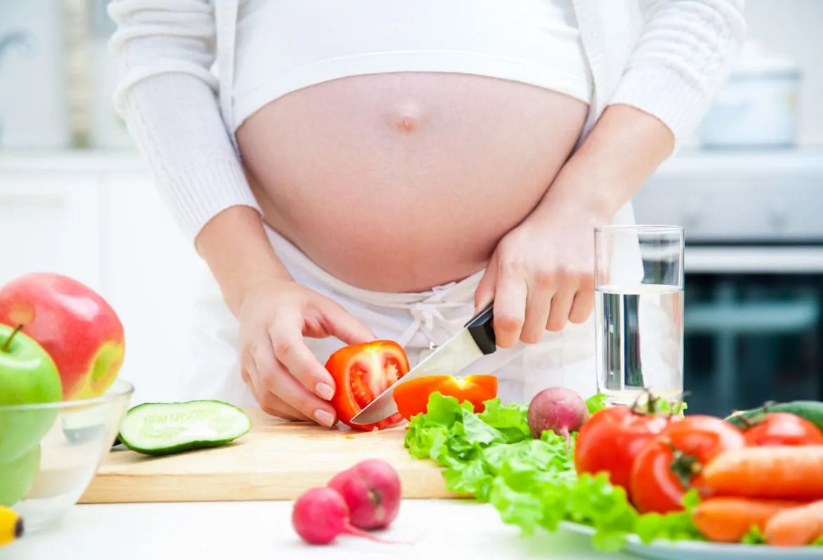 schwangere Frau kocht gesunde ernährung gegen Müdigkeit schwangerschaft